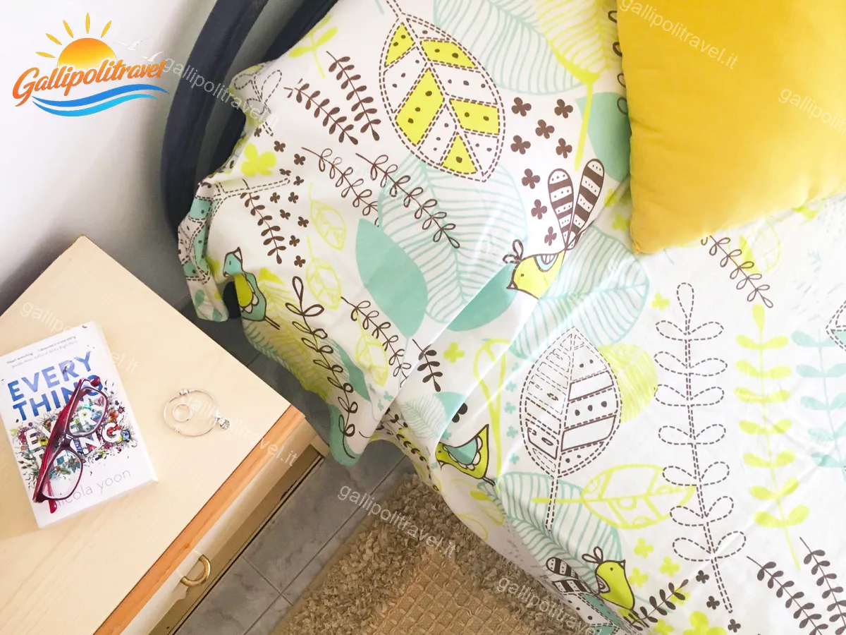 Particolare del letto del Bilocale La Vela con coperta a uccellini e comodino