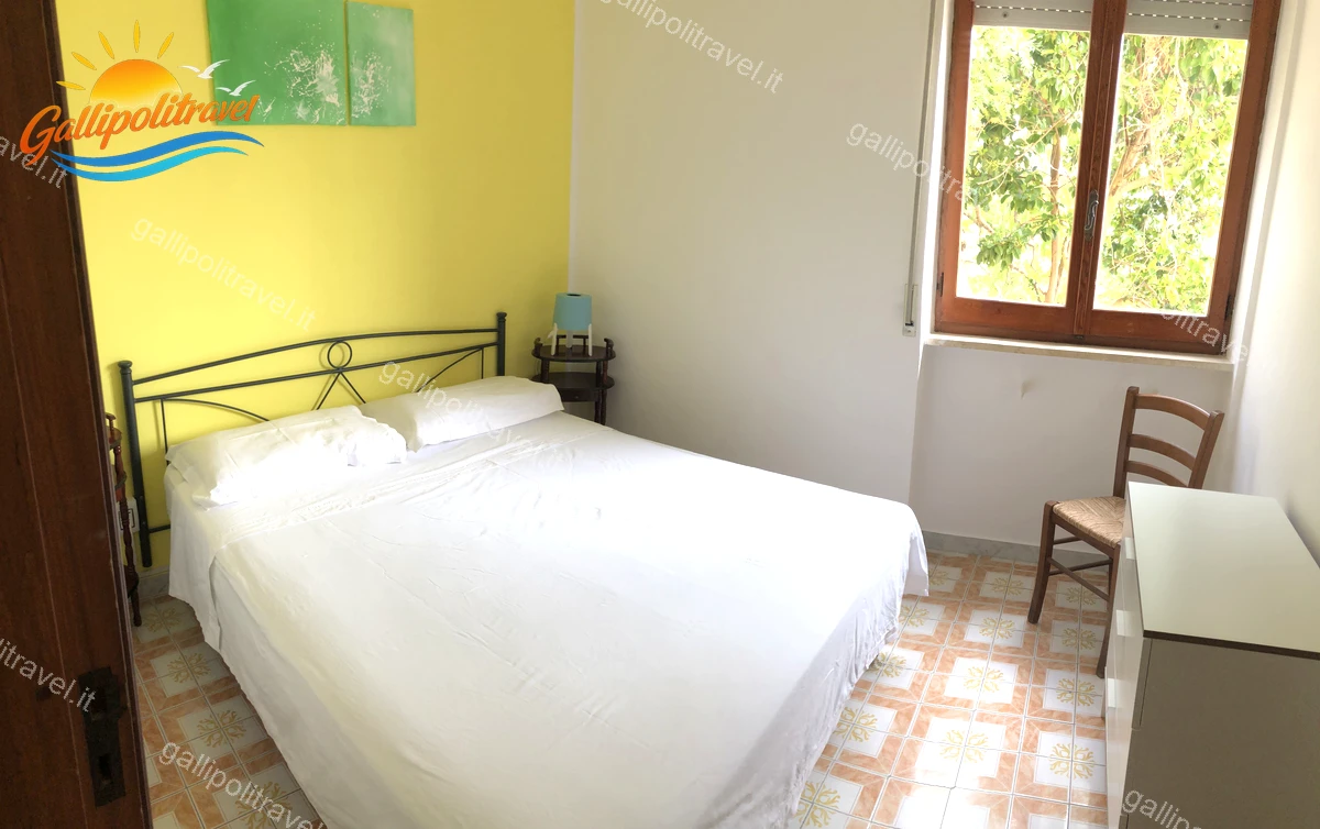 Chambre jaune avec tête de lit en fer forgé, appartement de quatre pièces Via dei Tigli Baia Verde