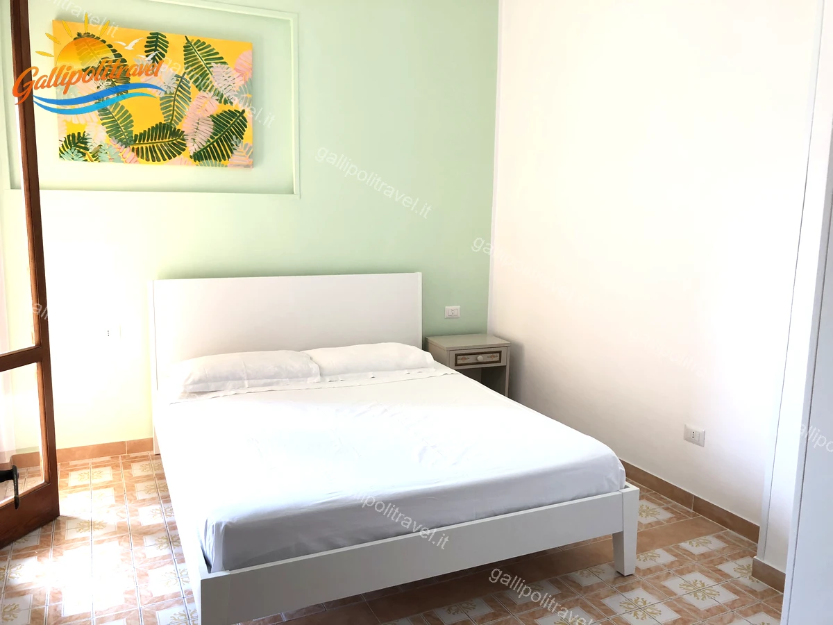 Chambre aux murs menthe et tête de lit blanche, appartement de quatre pièces Via dei Tigli Baia Verde