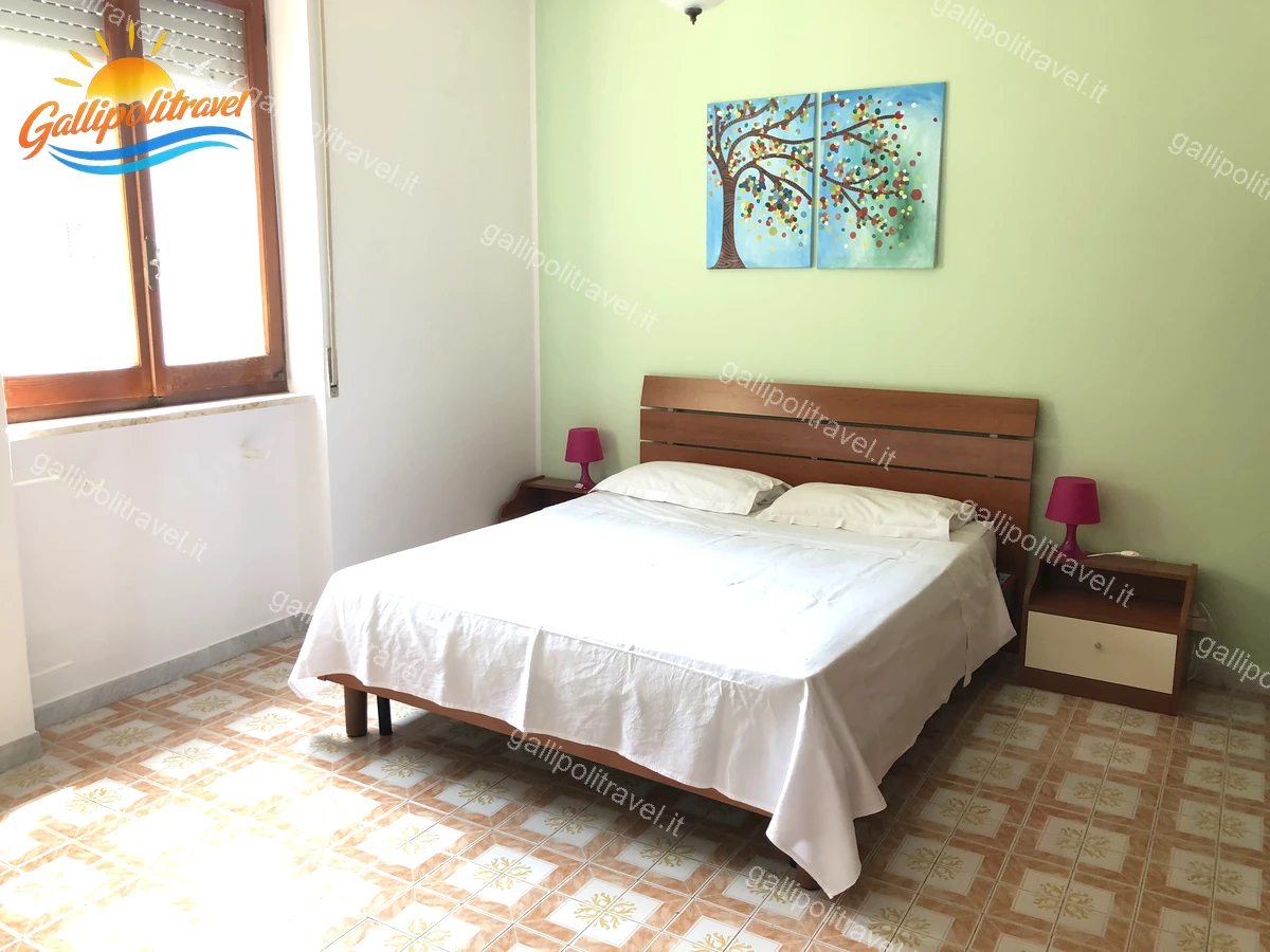 Chambre avec murs verts et tête de lit en bois, Appartement 4 pièces Via dei Tigli Baia Verde