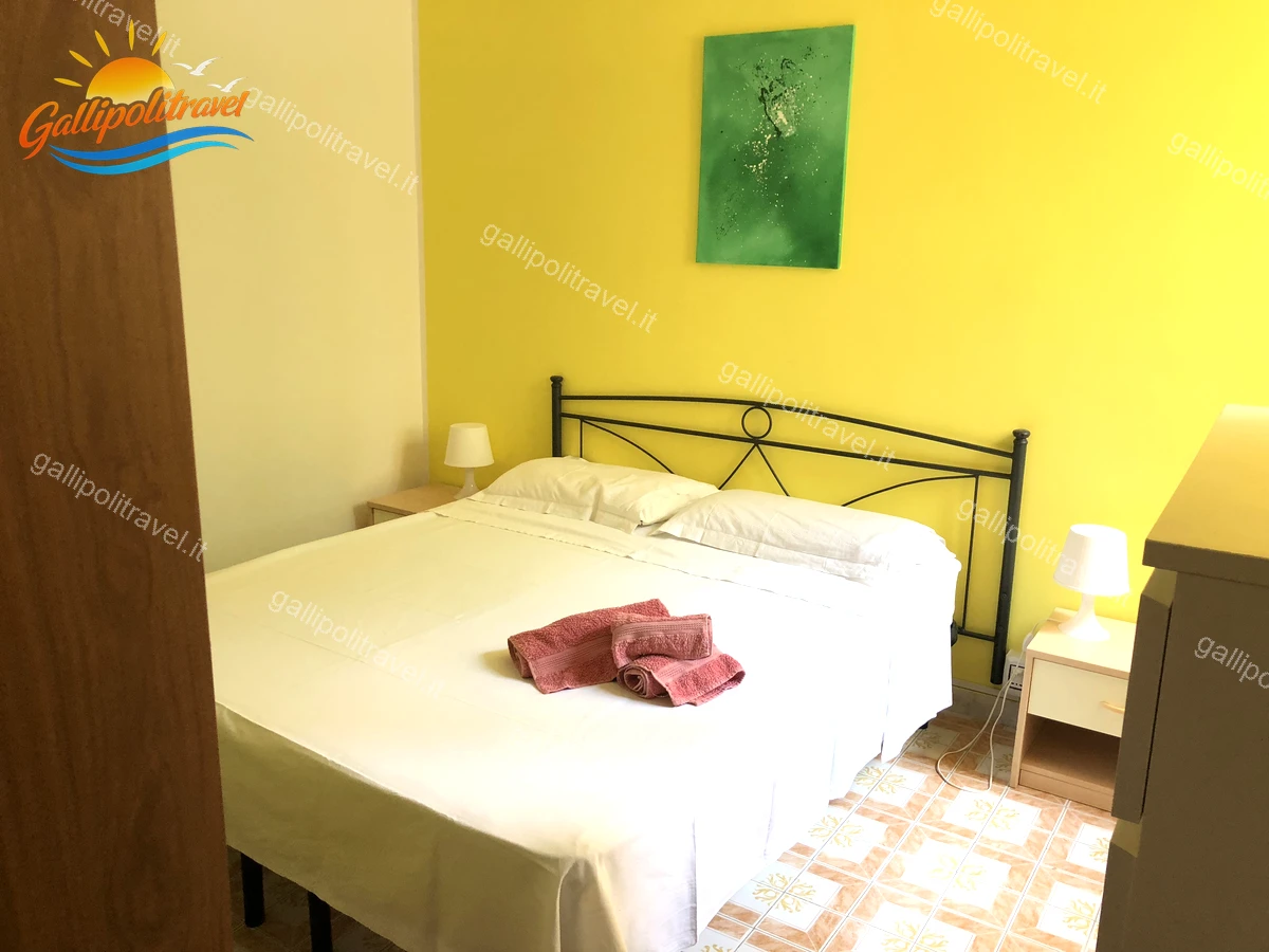 Chambre avec mur jaune et accès au balcon, Appartement de quatre pièces Via dei Tigli Gallipoli