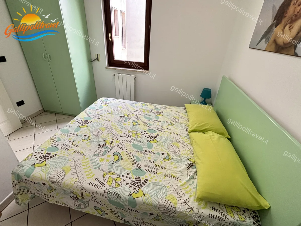 Chambre avec armoire verte et couverture à motifs de l'appartement trois pièces B2/3, Rosa Virginia Gallipoli