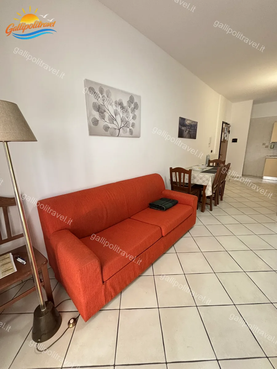 Séjour avec canapé rouge et lampadaire de l'appartement trois pièces B2/3, Residence Rosa Virginia Gallipoli