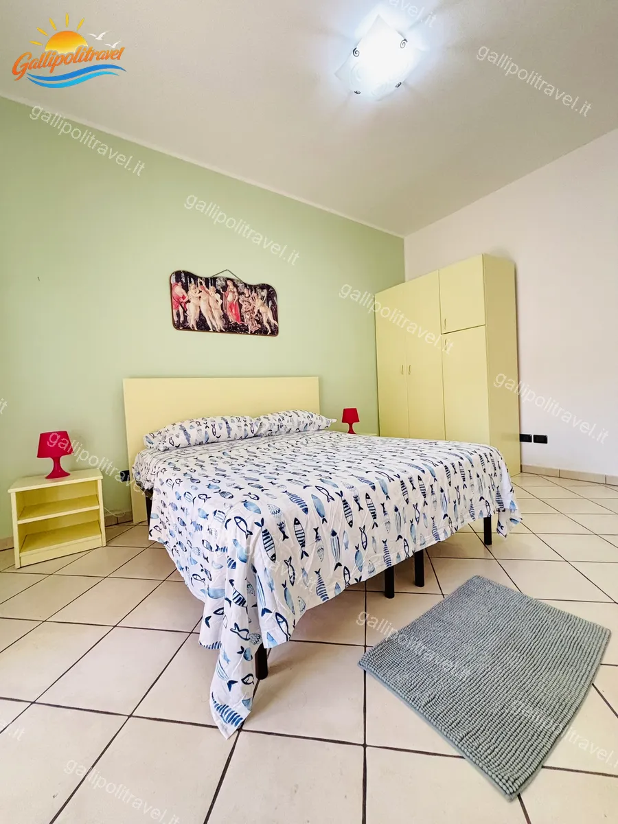 Camera matrimoniale con coperta a pesci e lampade rosse del Trilocale B2/4 Rosa Virginia