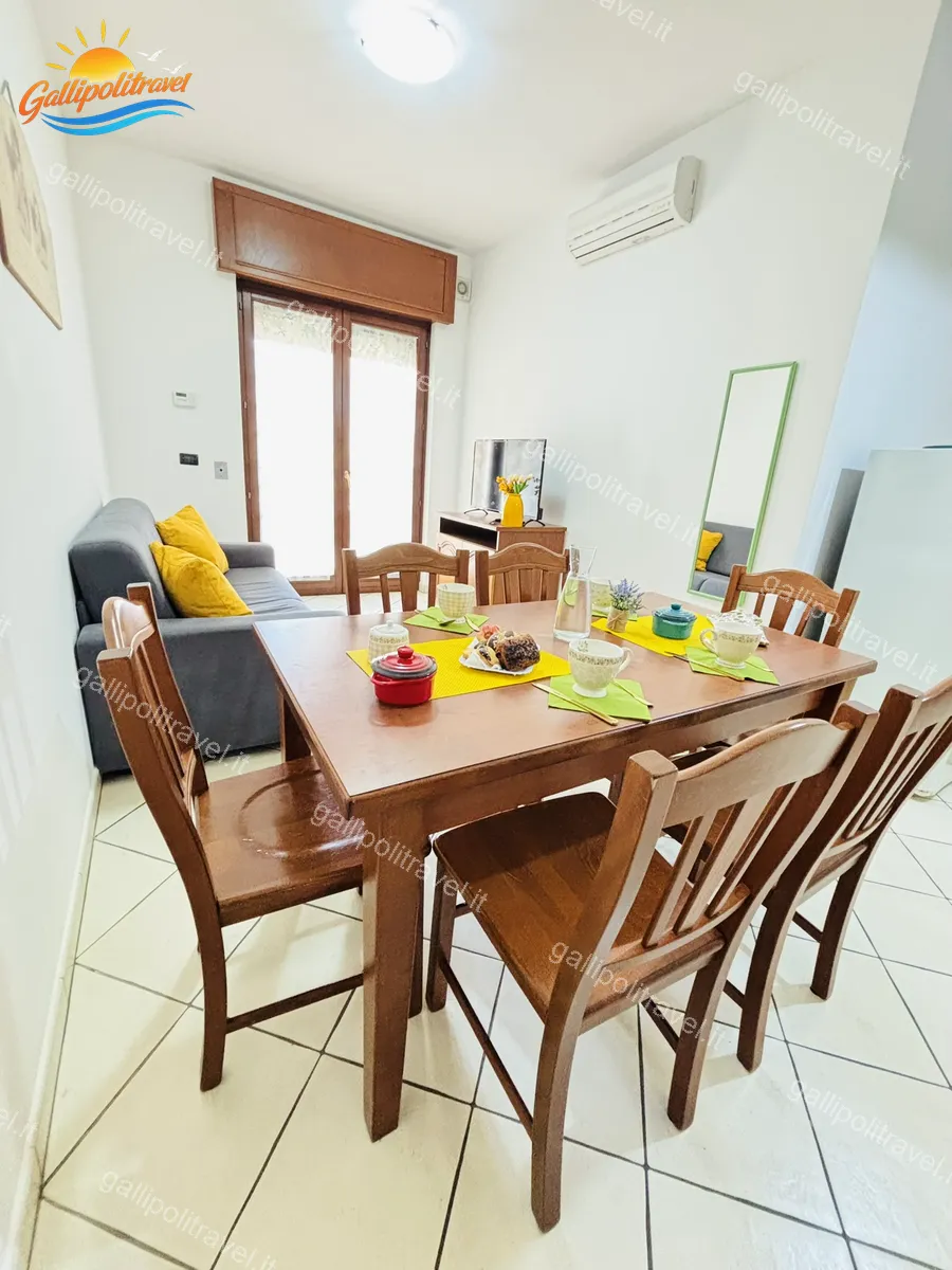 Zona pranzo con divano e cuscini gialli del Trilocale B2/4 Rosa Virginia Gallipoli