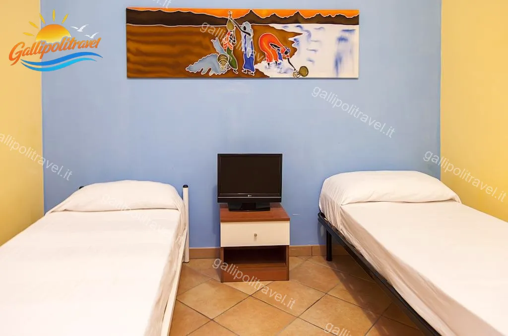 Einzelzimmer mit blauer Wand und afrikanischer Malerei der Dreizimmerwohnung F1/1, Rosa Virginia