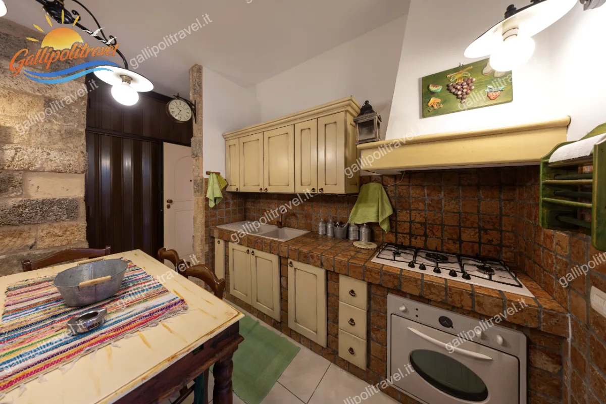 Particolare della cucina in muratura completamente attrezzata nel Trilocale Green, con focus sul forno, il piano cottura a gas, la cappa e i classici pensili in legno chiaro