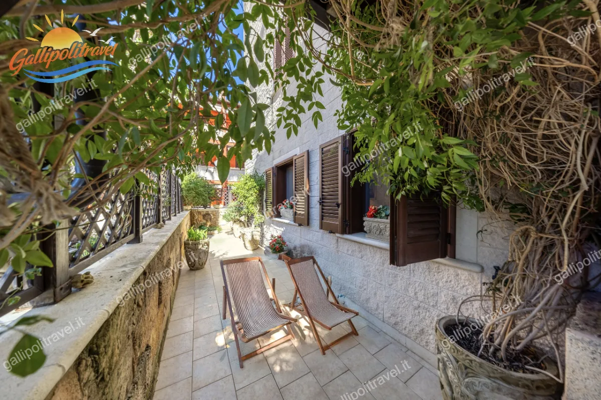 Lungo e curato patio privato ombreggiato da piante rampicanti, allestito con due sedie a sdraio per il massimo relax nel Trilocale Green