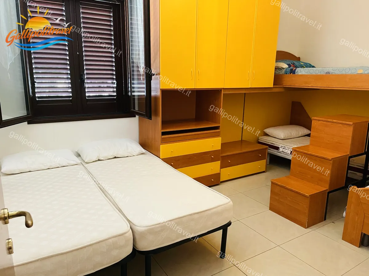 Bedroom with yellow wardrobe of the three-room apartment Orange, Residenza Marina Baia Verde