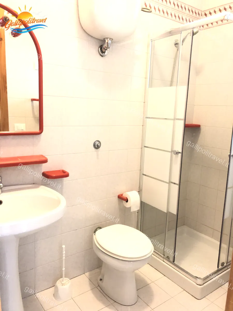 Salle de bain avec miroir cadre rouge de l'appartement trois pièces Tamerici 02, Baia Verde Gallipoli