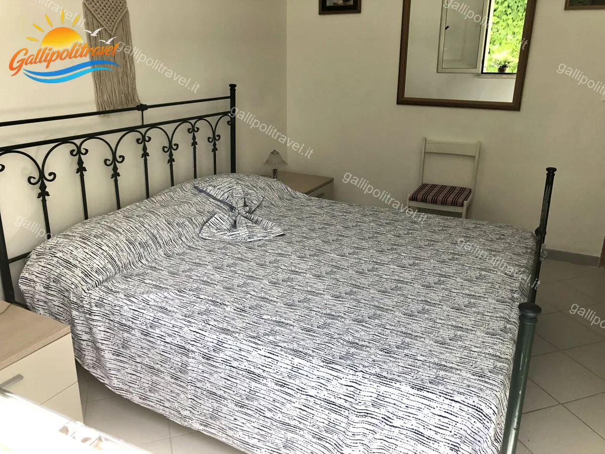 Chambre double avec couvre-lit rayé de l'appartement trois pièces Tamerici 02, Baia Verde Gallipoli