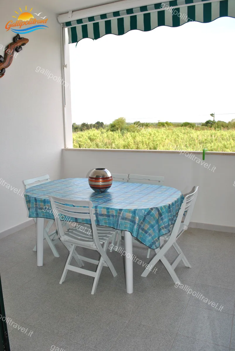 Balcone del Trilocale Girasole con tavolo azzurro e vista sulla campagna di Baia Verde